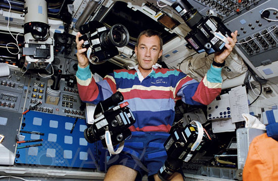 Terrence Wilcutt juggles five cameras onboard the Space Shuttle